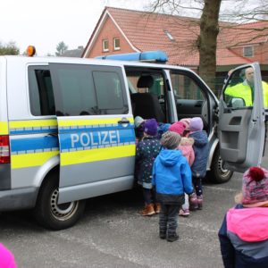 Kinder steigen in ein großes Polizeifahrzeug ein