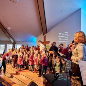 Kinder und Mitarbeiter Spatzennest führen ein Lied vor